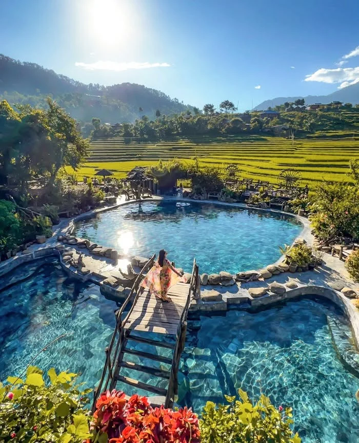 Bể khoáng nóng ngoài trời ở Trạm Tấu, phía xa là ruộng bậc thang và núi