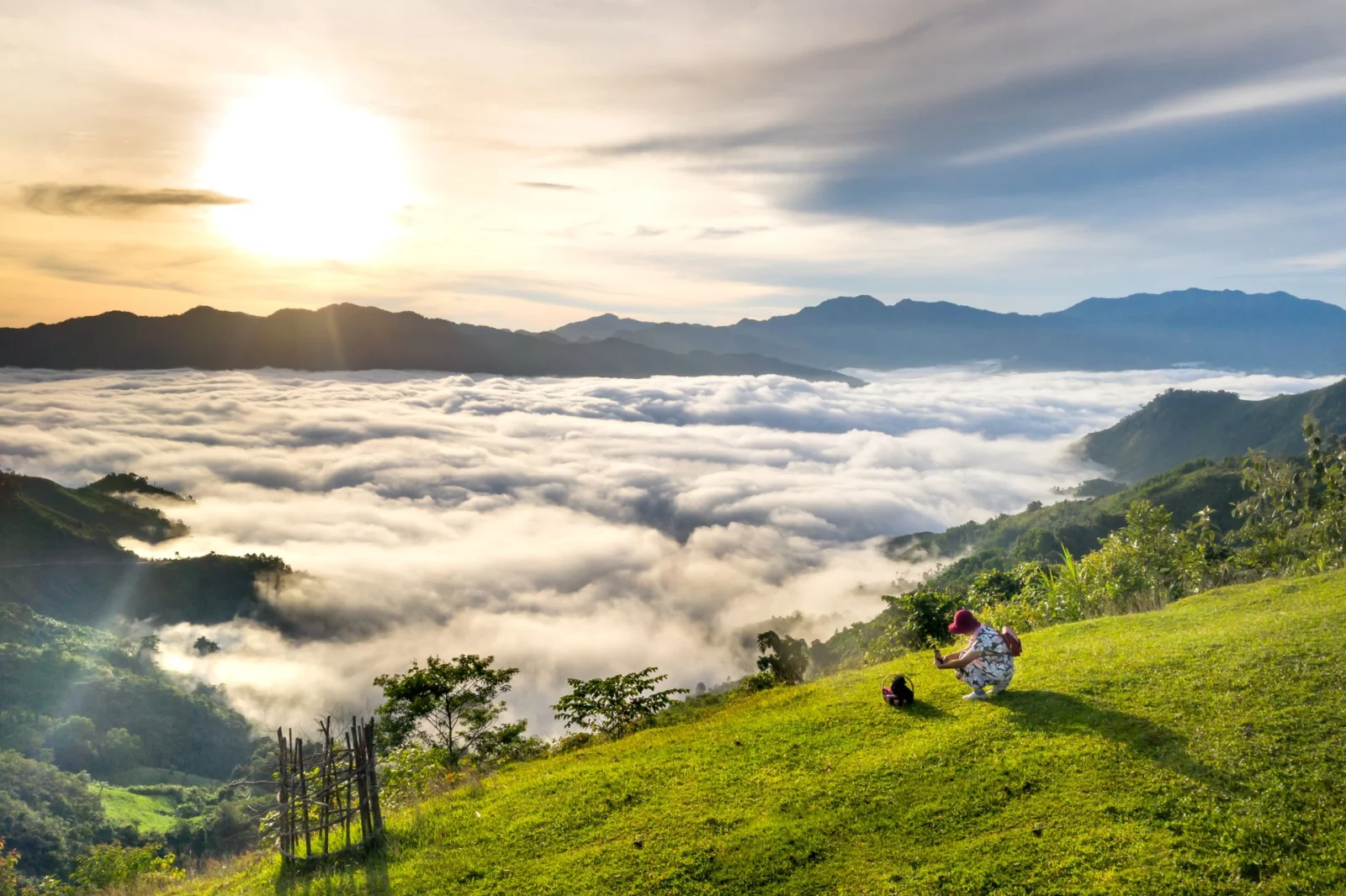 Biển mây trắng phủ thung lũng lúc bình minh ở vùng núi Tây Bắc, du khách ngồi chụp ảnh trên đồi cỏ